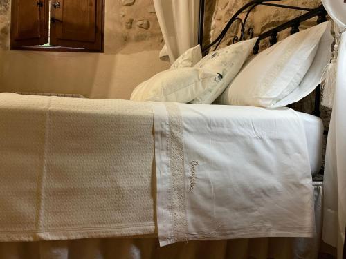 a bed with white sheets and pillows on it at Casa Lidia - Antigua Posada Real in Valderrobres