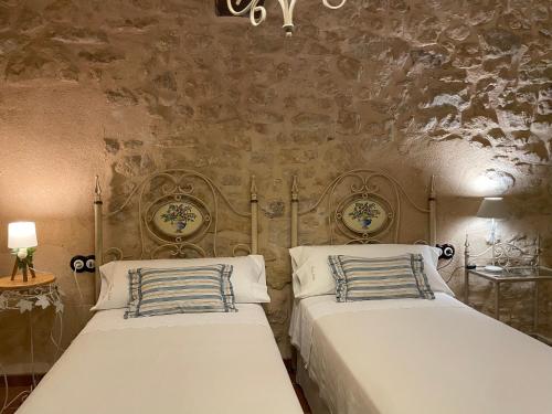 two beds in a bedroom with a stone wall at Casa Lidia - Antigua Posada Real in Valderrobres