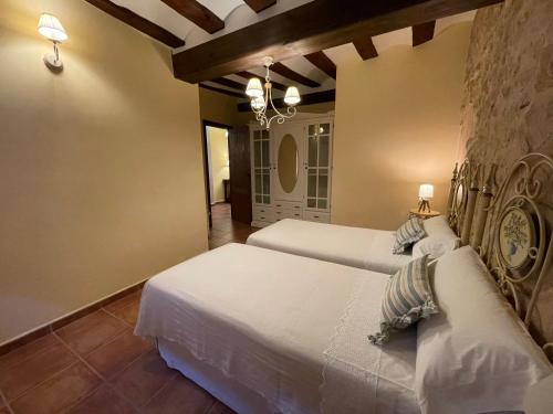 a bedroom with two beds and a chandelier at Casa Lidia - Antigua Posada Real in Valderrobres