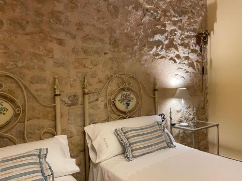 a bedroom with two beds and a stone wall at Casa Lidia - Antigua Posada Real in Valderrobres