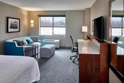 a hotel room with a bed and a desk with a television at Courtyard Seattle Sea-Tac Area in Tukwila