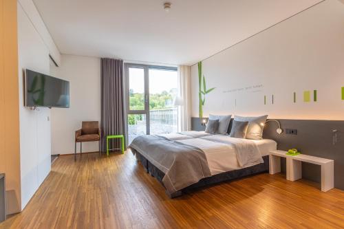 a bedroom with a large bed and a tv at LAGO hotel & restaurant am see in Ulm