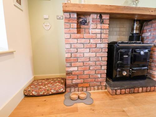 a room with a brick fireplace with a pair of slippers at Garreg Wen in Holywell
