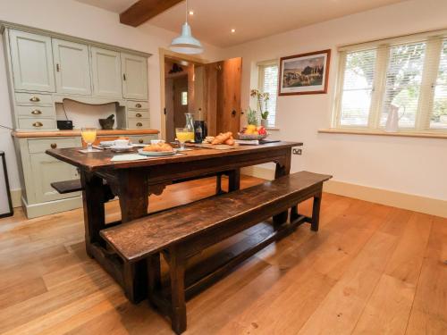 a kitchen with a wooden table and a bench at Garreg Wen in Holywell