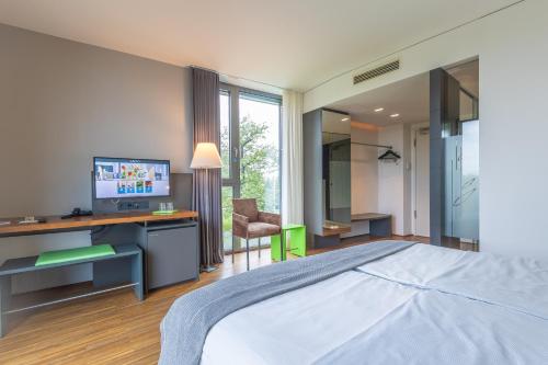 a bedroom with a bed and a desk with a television at LAGO hotel & restaurant am see in Ulm