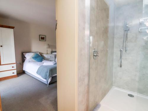 a bathroom with a shower and a bedroom with a bed at Garreg Wen in Holywell
