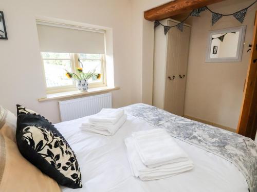 a white bed with two white towels on top of it at Garreg Wen in Holywell