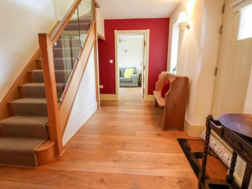a hallway of a home with a staircase and red walls at Garreg Wen in Holywell