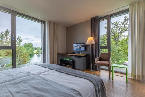 Schlafzimmer mit einem Bett, einem Schreibtisch und Fenstern in der Unterkunft LAGO hotel & restaurant am see in Ulm