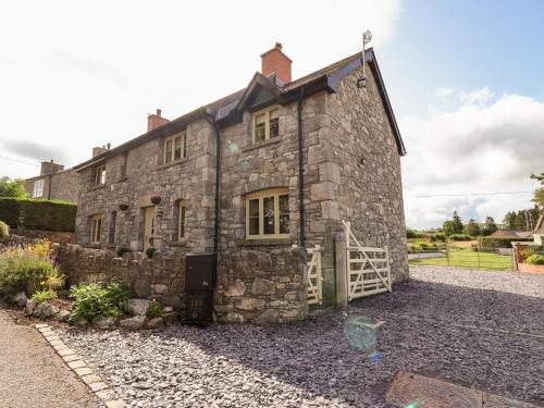 an old stone house with a gate in a yard at Garreg Wen in Holywell
