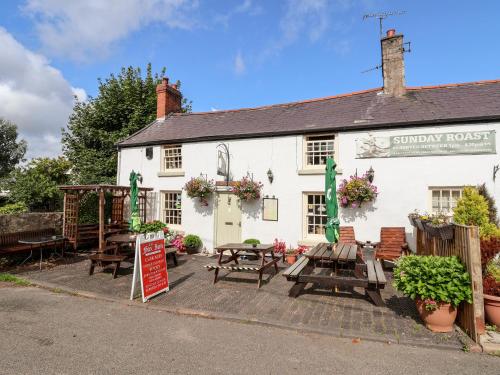 a white building with tables and benches in front of it at Garreg Wen in Holywell