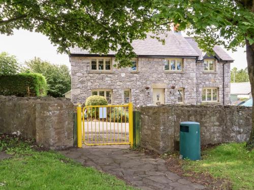 a yellow gate in front of a stone house at Garreg Wen in Holywell