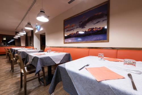 uma fila de mesas num restaurante com toalha de mesa branca em Hotel Fortini em Madonna di Campiglio