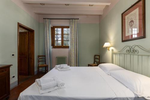sypialnia z dużym białym łóżkiem z ręcznikami w obiekcie Fattoria la Gigliola - Il Frantoio w mieście Montespertoli
