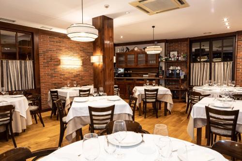 a restaurant with white tables and chairs and a brick wall at Hotel Restaurante De Torres in Felechosa