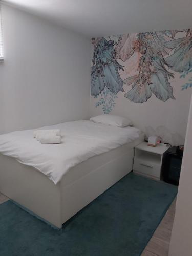 a bedroom with a white bed with a flower mural on the wall at Comfort Rooms Remiza - Free Private Parking - Self check-in in Zagreb