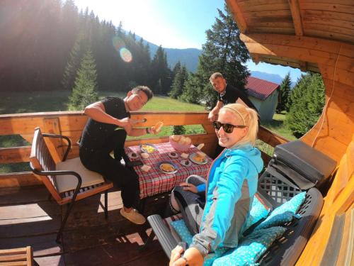 un grupo de personas sentadas en una mesa en el porche de una cabaña en Peaks of the Balkans Trail 192 km -- Hostel Panorama -- en Peje