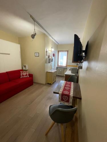a living room with a red couch and a table at Monolocale piccolo ed accogliente - CIR 0021 - in Aosta