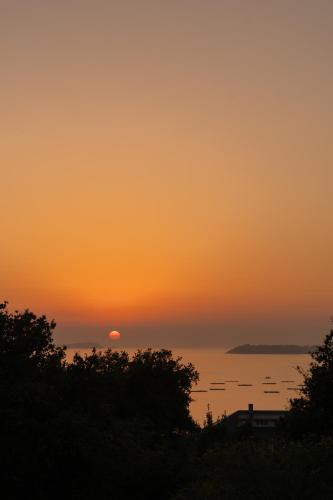 a sunset over the water with the sun in the sky at Cabañas de Xarás, Mimosa in Marín