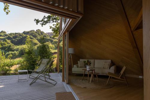 a living room with a couch and chairs on a deck at Cabañas de Xarás, Mimosa in Marín