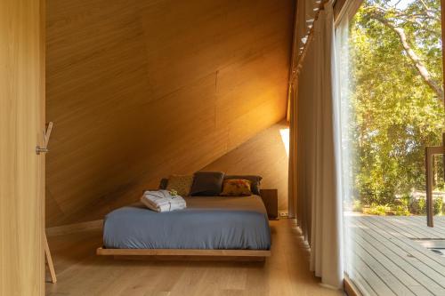 a bed in a room with a large window at Cabañas de Xarás, Mimosa in Marín
