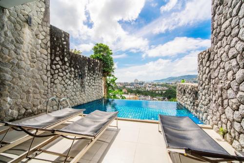 a patio with two chairs and a swimming pool at Patong Villa1：3卧泳池别墅【两个海景房】 近班赞江西冷海滩【中文管家】提供摩托车 in Patong Beach