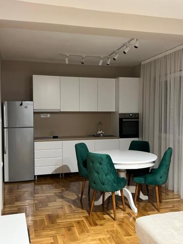 a kitchen with a white table and green chairs at Kali Apartments in Bitola