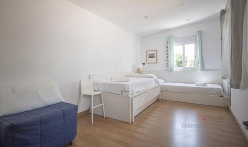 Un dormitorio blanco con 2 camas y una silla en TH46 Casa con piscina 900 m de la playa Arrebassada en Tarragona