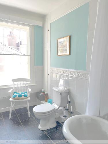 a bathroom with a white toilet and a chair at Portland House in Whitchurch