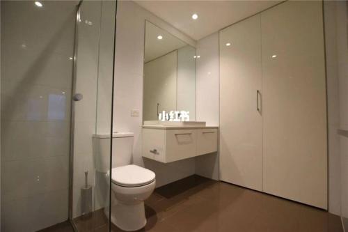 a white bathroom with a toilet and a shower at Quiet CBD 3b2b apartment + free parking in Melbourne