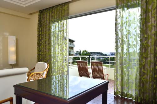 a living room with a table and a large window at EXES Ishigaki in Ishigaki Island