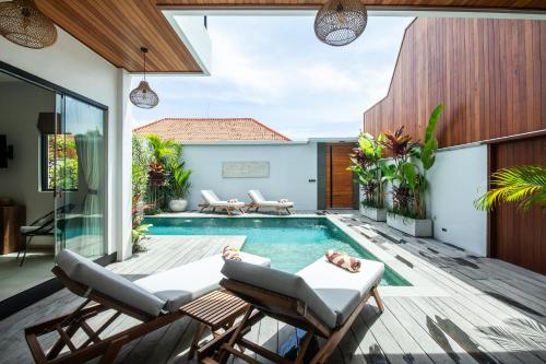 an outdoor patio with a swimming pool and patio furniture at Zayana Villas Resort Seminyak in Seminyak