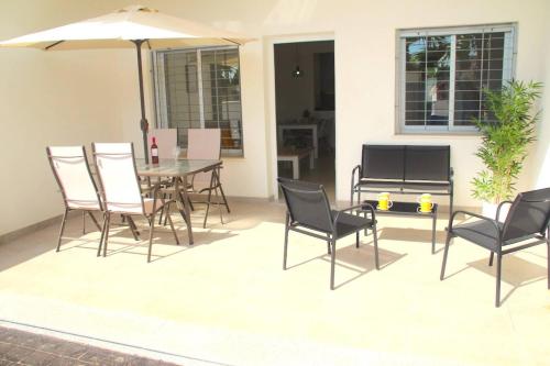 een patio met een tafel en stoelen en een parasol bij Oasis Holiday House in Orihuela