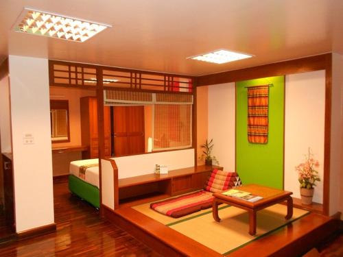 a room with a bed and a table and a couch at B.S. Court Hotel Sathorn in Bangkok