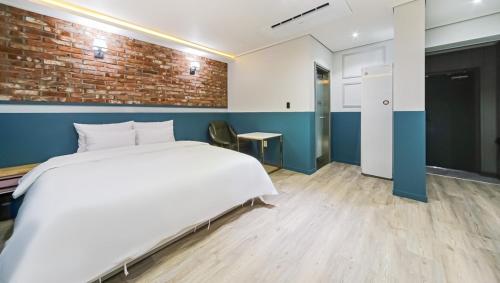 1 dormitorio con cama blanca y pared de ladrillo en Hotel Cheese Ulsan Samsan, en Ulsan