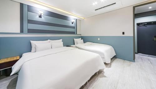 a bedroom with a large white bed and a window at Hotel Cheese Ulsan Samsan in Ulsan