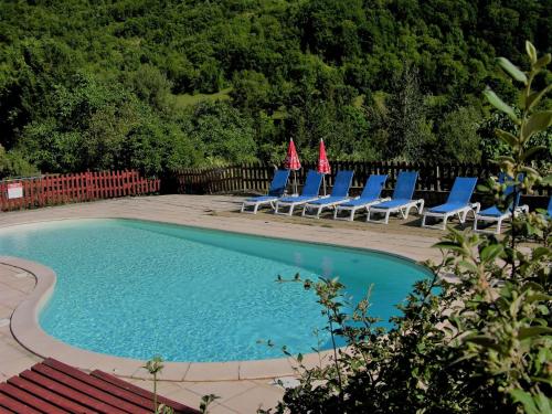 a group of chairs and a swimming pool with chairs and umbrellas at la Frégière Chalets in Clairvaux-dʼAveyron