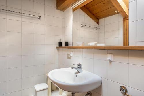 lavabo blanco en el baño con azulejos blancos en Appartamento Cinzia, en Moena