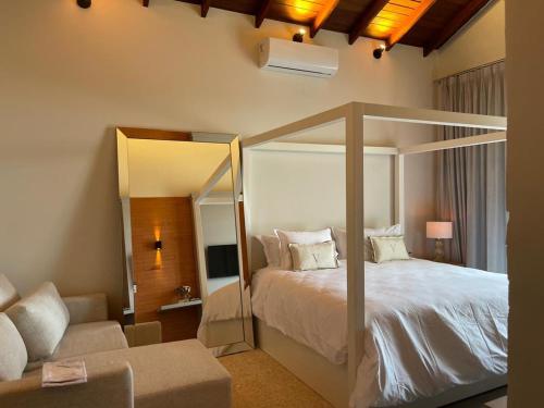 um quarto com uma cama, um espelho e um sofá em Casa do Valle - Hotel Boutique em Chapada dos Guimarães