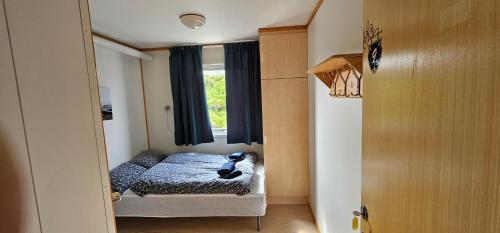 a small bedroom with a bed and a window at Gamvik brakkebo as in Gamvik