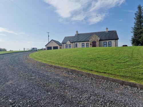 a house on a grassy hill next to a road at 3 bedroom detached bungalow in Dromore