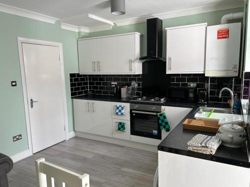 Room in Trumpington London في لندن: مطبخ بدولاب أبيض وقمة كونتر أسود
