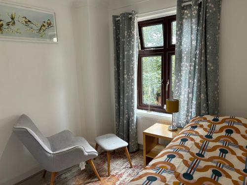 Room in Trumpington London في لندن: غرفة نوم بسرير وكرسي ونافذة