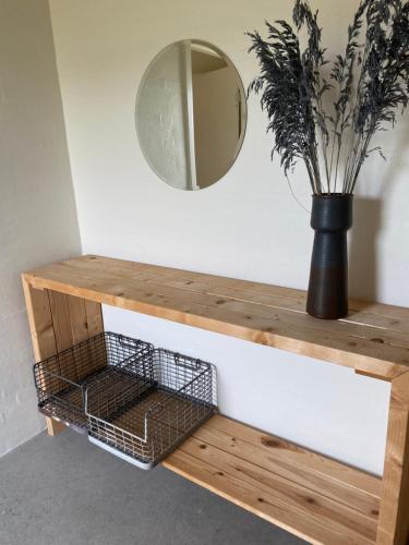 a wooden console table with a mirror and a plant at Country Home in Hejnsvig