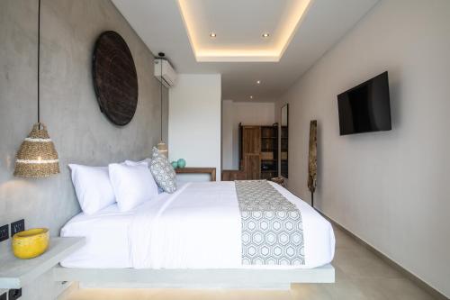 a bedroom with a white bed and a tv at Zayana Villas Resort Seminyak in Seminyak