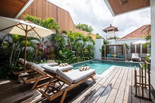 an outdoor swimming pool with a lounging chair and a lounging area at Zayana Villas Resort Seminyak in Seminyak