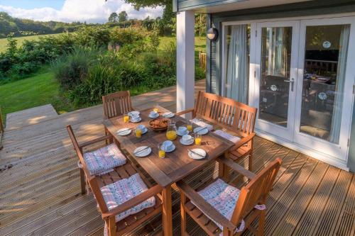a wooden table with four chairs on a deck at Trewhiddle Retreat V7 by Together Travel - Luxury 3-Bedroom Villa in St Austell