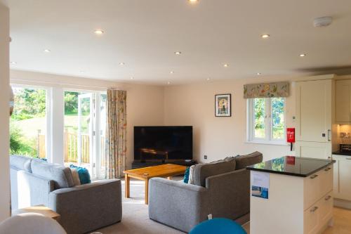 a living room with couches and a table at Trewhiddle Retreat V7 by Together Travel - Luxury 3-Bedroom Villa in St Austell