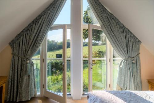 a bedroom with a large window looking out at a field at Trewhiddle Villa 07 in St Austell