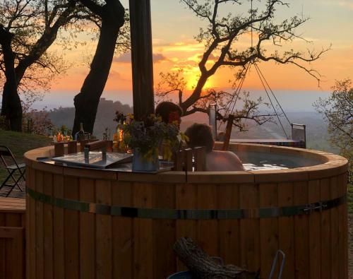 a person in a hot tub with a sunset in the background at Castello di Granarola Relais - Adults Friendly - in Gradara